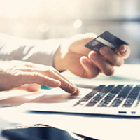 Image of a hand holding a credit card with laptop