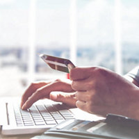 Image of a hand holding a credit card with laptop